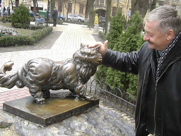 stone cat мужчина гладит памятник кошке